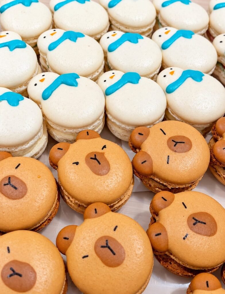 Macarons gallery: Capybara-face macarons in front of snowman macarons with blue icing scarves