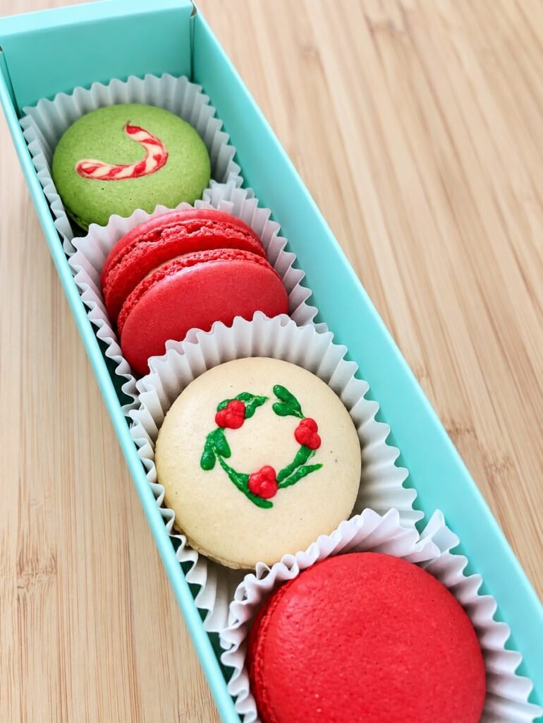 Christmas macarons in a mint green gift box, decorated with a candy cane and a holly wreath