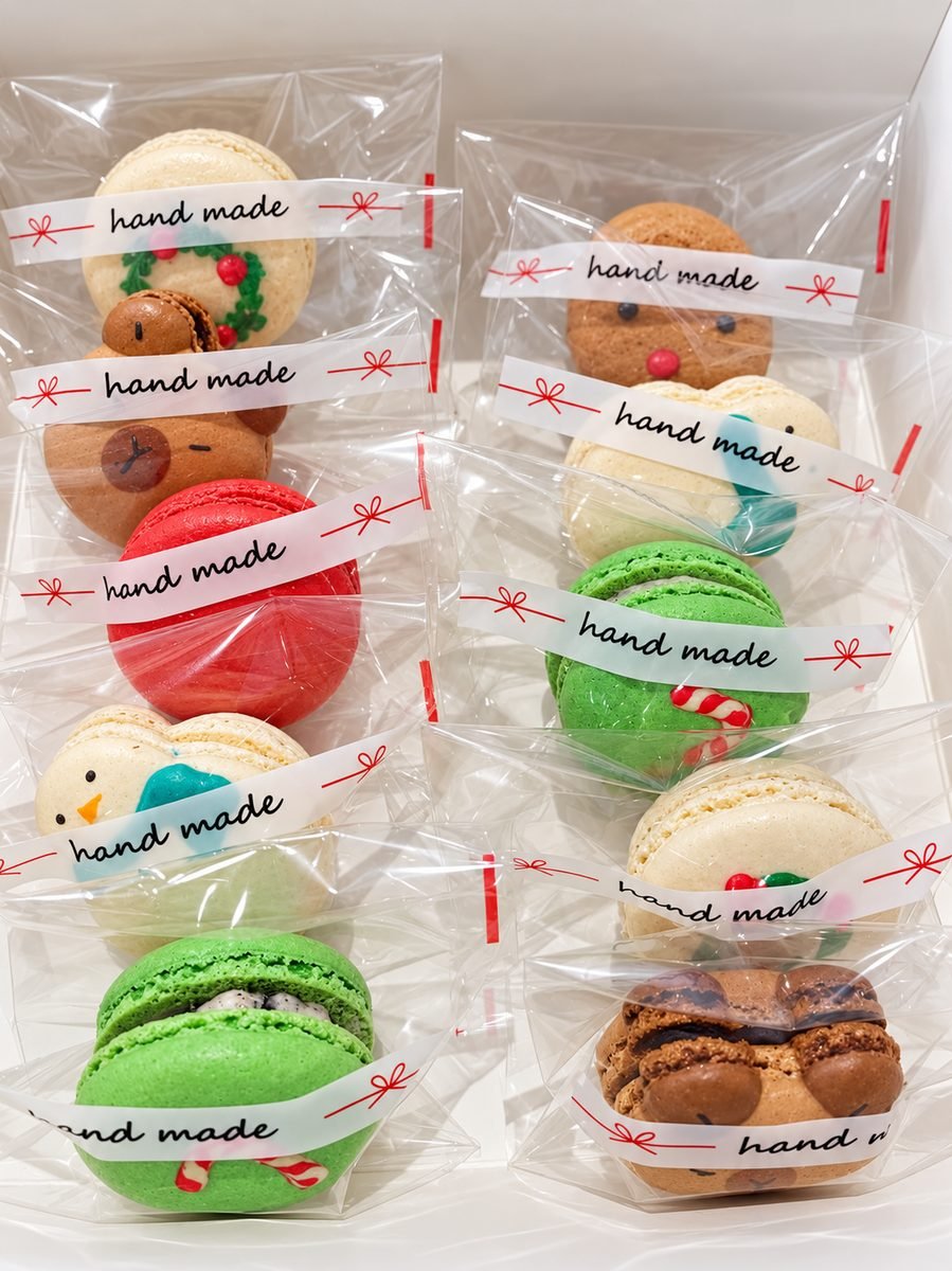 Individually wrapped handmade Christmas macarons decorated as a reindeer, a snowman and a holly wreath