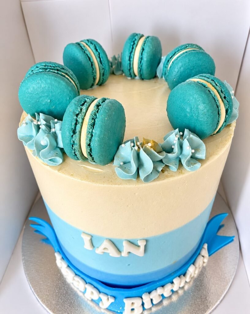 Teal and cream birthday cake crowned with a ring of matching teal macarons